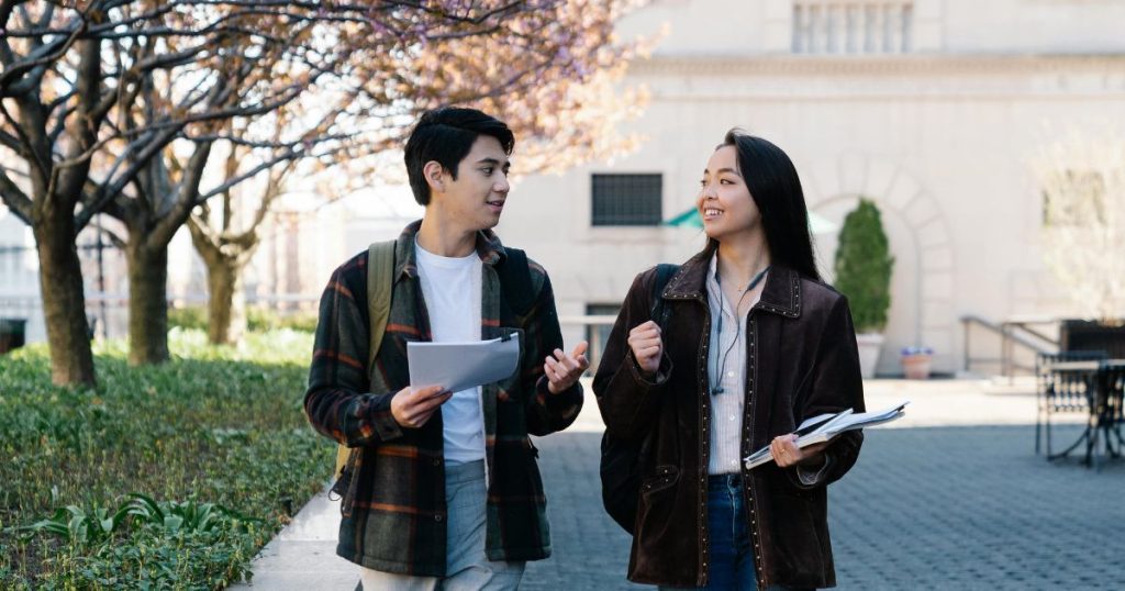 Two international students discuss their studies on the university campus. This represents recipients of the Korea University Club Scholarship.