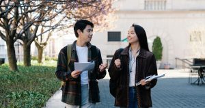 Two international students discuss their studies on the university campus. This represents recipients of the Korea University Club Scholarship.