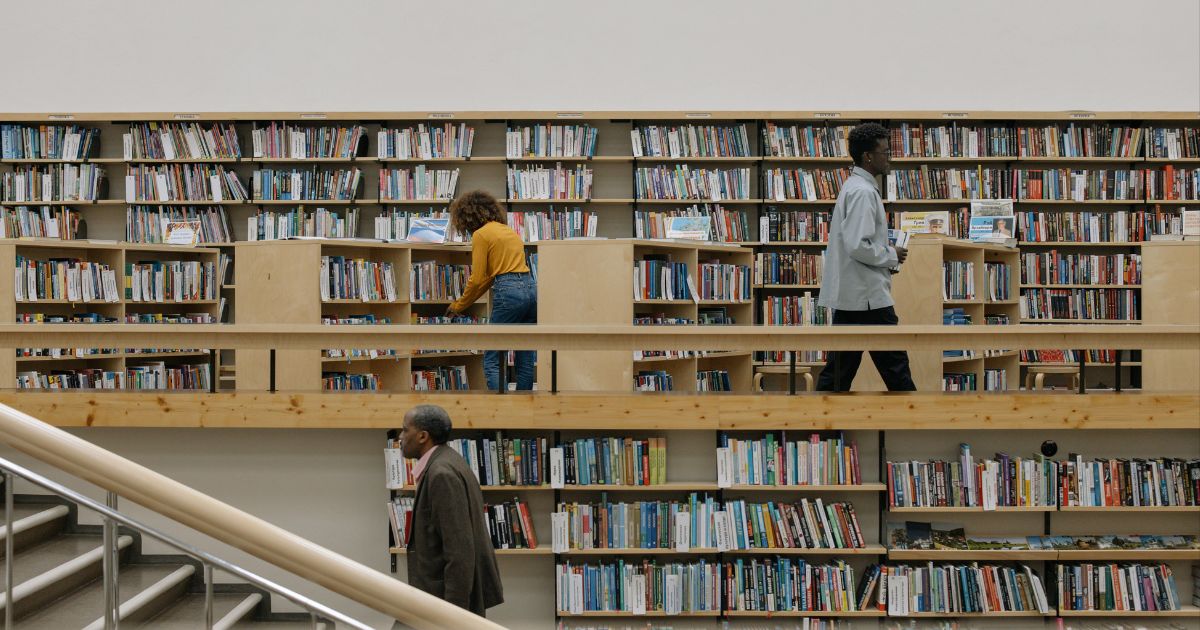 Students browsing books in a well-stocked library, symbolizing academic excellence and opportunities like the International Dean's Scholarship.