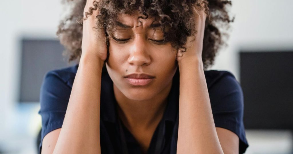 A young woman holding her head in frustration, representing the dark side of scholarships including financial burdens and emotional strain.