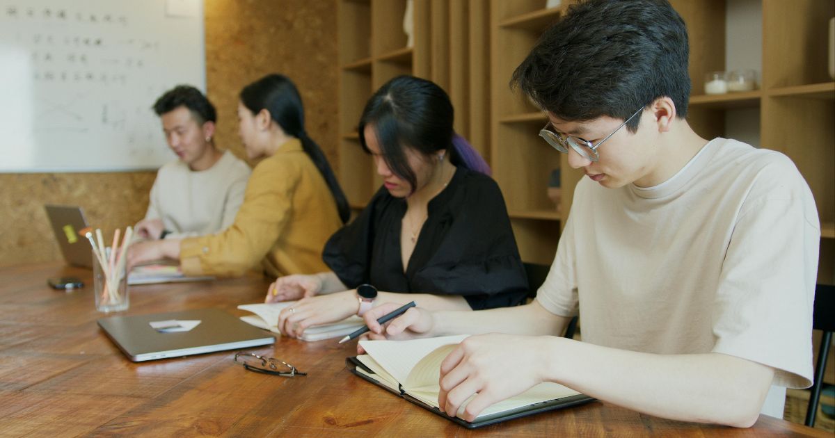 Students studying together in a classroom and taking notes. This is an ideal representation of students of the Overseas Koreans Scholarship in South Korea.