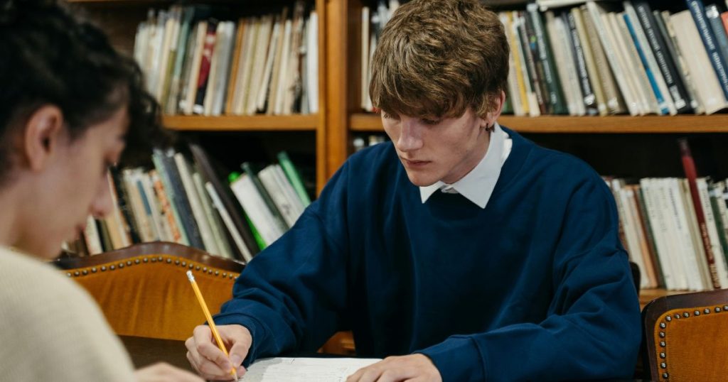 Two students studying in a library, preparing for their Master of Business Administration (MBA) scholarship application.